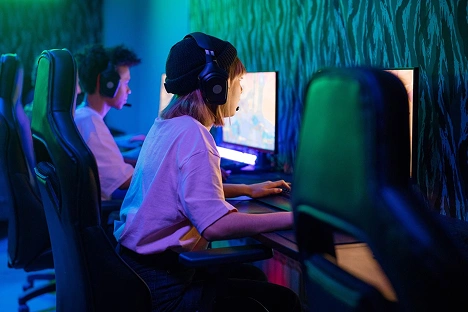 Vrienden die genieten van multiplayer-pc-games in een moderne gamingclub, uitgerust met krachtige computers en gamingstoelen.