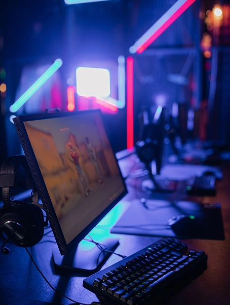 Professionele gaming-pc-opstelling met RGB-verlichting, gamingmonitor, mechanisch toetsenbord en headset in een moderne gamekamer.