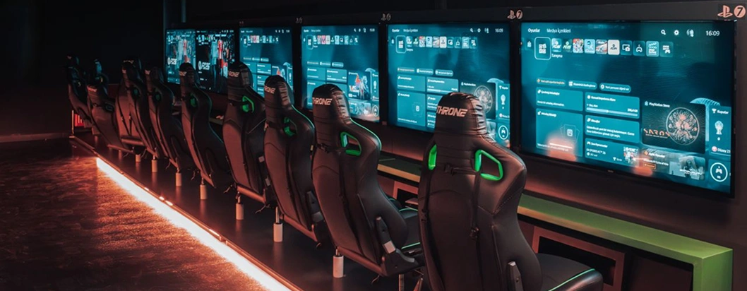 Moderne gamingzone met meerdere PlayStation-stations, ergonomische gamingstoelen en grote beeldschermen voor multiplayer-sessies op de console.