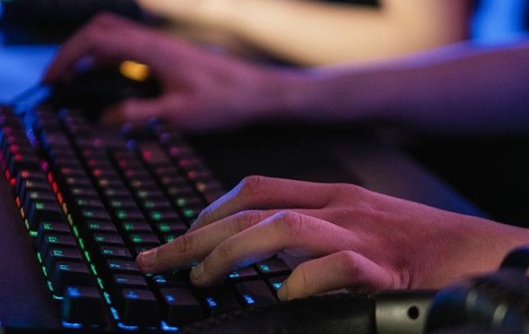 Close-up van een mechanisch RGB-gamingtoetsenbord tijdens een online gamesessie, met verlichte toetsen en een gamingheadset.
